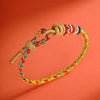 Close up of a multicolored braided rope bracelet with a gold dragon charm and knot closure