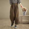 Front view of woman wearing loose brown cotton harem pants with elastic waist