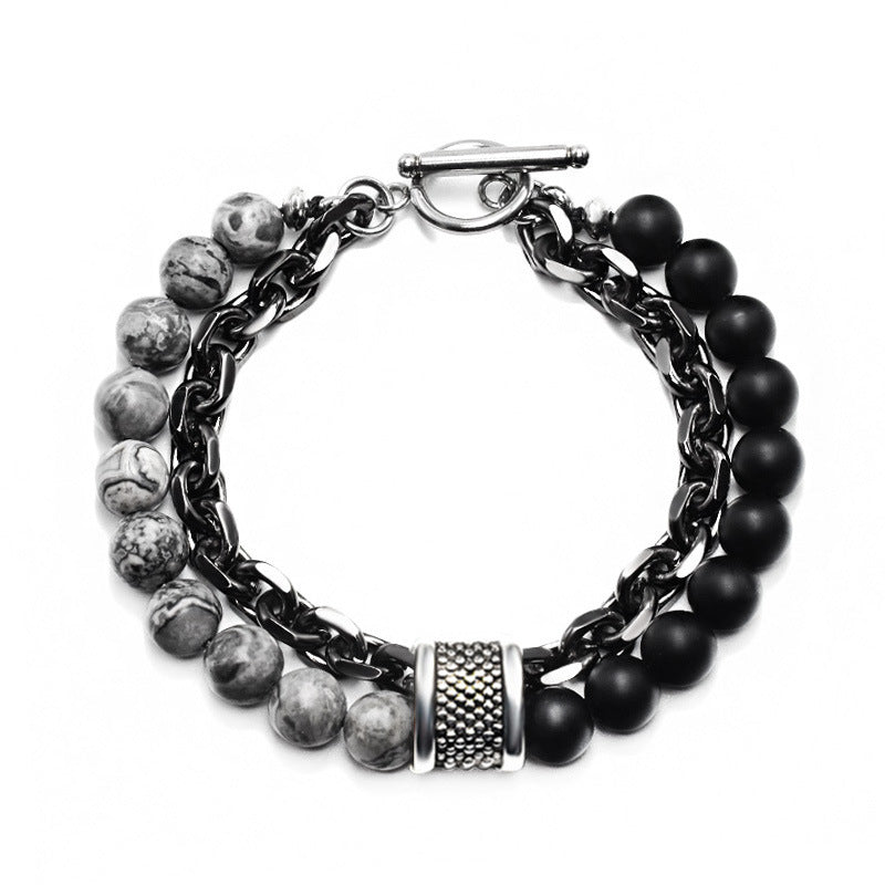 Double-strand men's bracelet with black matte beads and a dark metal chain on a leather surface