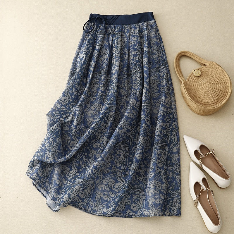 Blue floral linen midi skirt with drawstring waist laid flat next to accessories