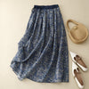 Blue floral linen midi skirt with drawstring waist laid flat next to accessories