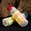 Bundles of handmade Nepal rope incense with red and blue tips on a dark surface