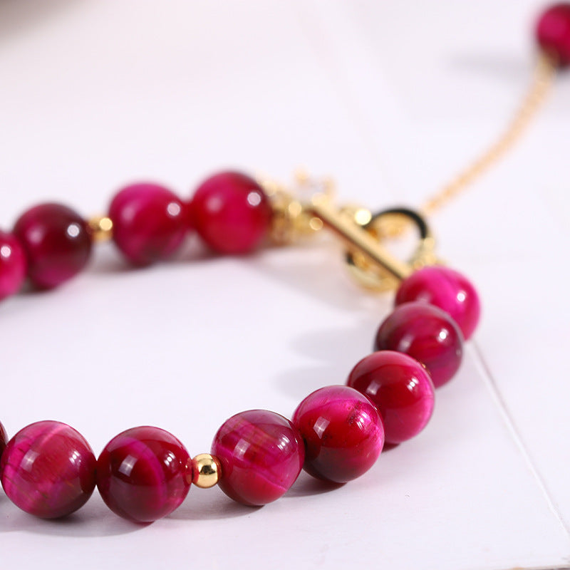 Close up of a pink glass bead bracelet with a gold fox pendant on a wrist