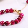 Close up of a pink glass bead bracelet with a gold fox pendant on a wrist