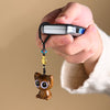 Hand holding a wooden cat charm attached to a car key fob