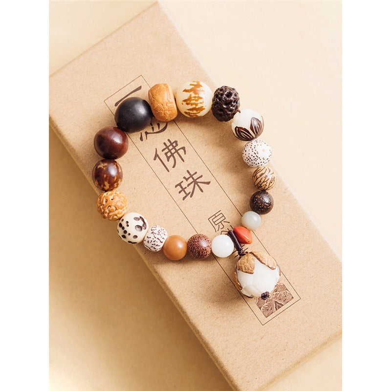 Woven bodhi seed bracelet with mixed beads and a white lotus charm on a box