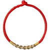 Close up of a red braided bracelet with a textured gold center knot