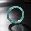 Two translucent blue-green jade bangles standing on a black reflective surface