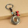 Antique copper key chain with dragon hook pendant and red beads attached to a car key
