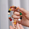 Hand holding a multicolored wooden bead bracelet with a tassel
