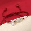 Close-up of a red braided bracelet with a silver snake charm and bead accents