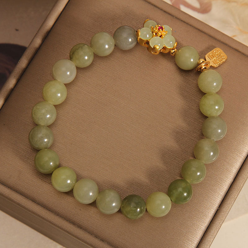 Green jade bead bracelet with gold four leaf clover and Fu charm on a box