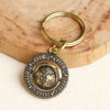 Close-up of a brass keychain with a rotatable center sphere on a wooden surface