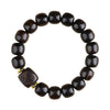 Close up of a dark wood bead bracelet with a carved square charm on a wrist