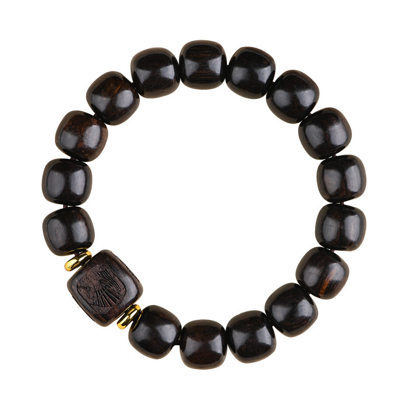 Close up of a dark wood bead bracelet with a carved square charm on a wrist