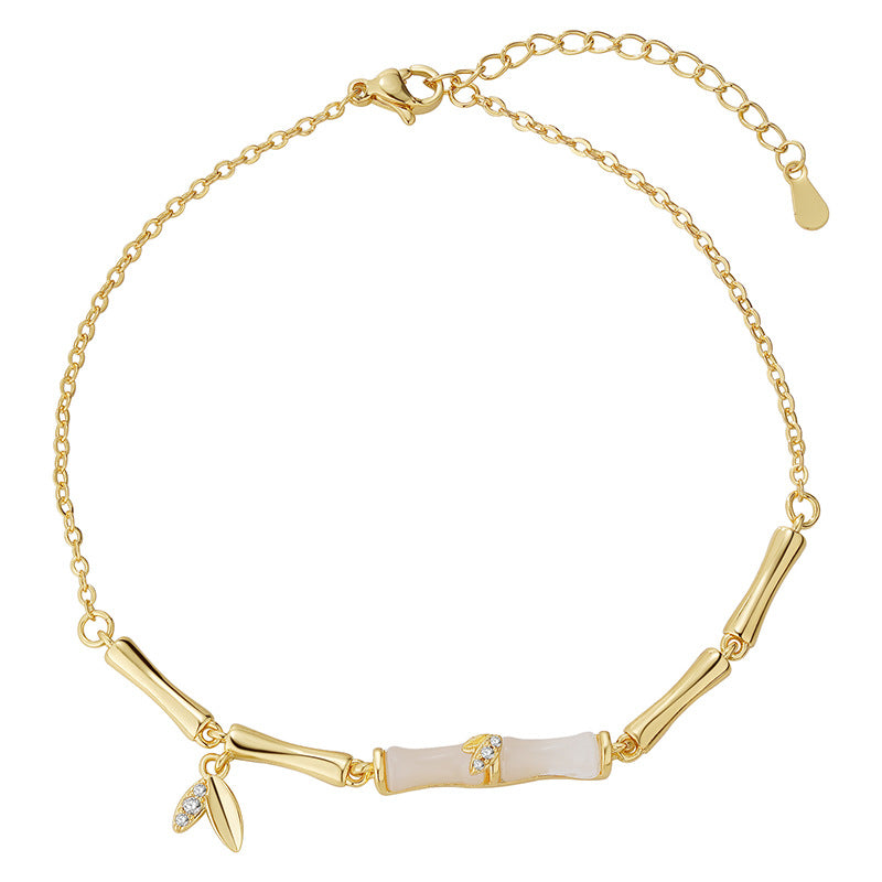 Close up of a gold tone copper anklet with bamboo links worn on an ankle