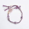 Purple and white woven rope bracelet with pink and purple crystal beads on a white background