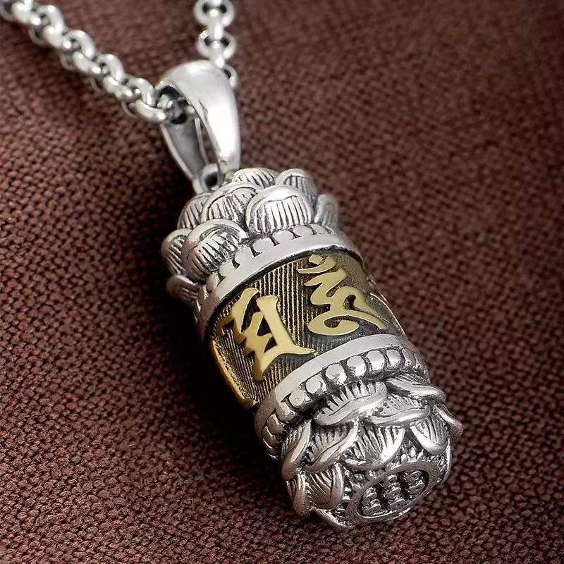 Close up of silver tone copper pendant with gold text on brown background