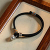Close up of the black braided bracelet showing the silver persimmon charm and woven detail