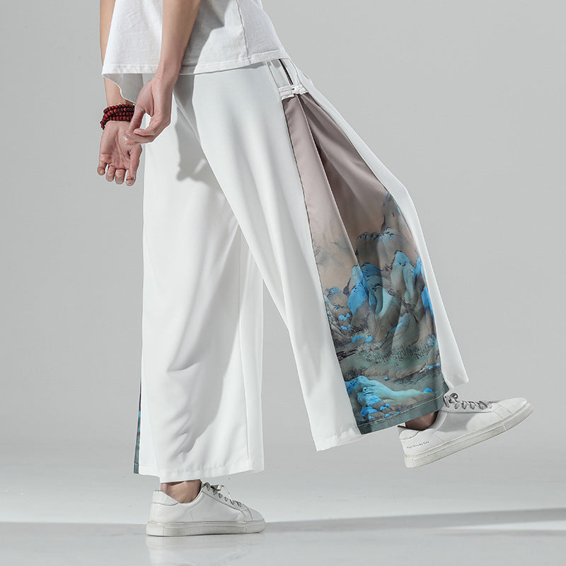 Model wearing white wide leg pants with blue mountain print on the side
