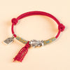 Silver koi fish charm on a red woven cord bracelet with a small hanging tag