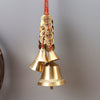 Close-up view of a brass bell with a red cord and ancient coins attached