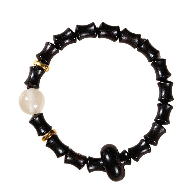 Close-up of black ebony bamboo joint bracelet with a white bead on a white background