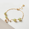 Close up of a gold tone bracelet with light green jade beads and a rose charm