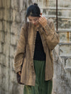 A woman wearing a loose-fitting, tie-dye linen jacket with frog buttons, standing on stone steps.