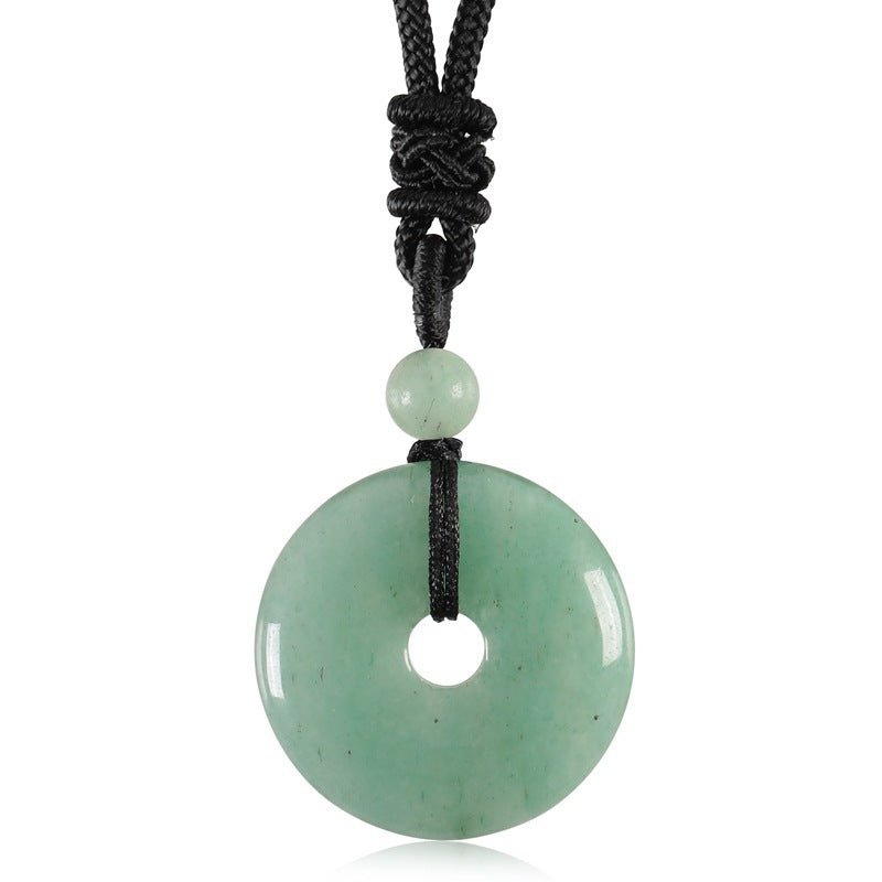 Close-up of a round green stone pendant on a black knotted cord against a white background