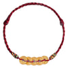 Gold tone five copper coins threaded onto a braided red cord bracelet
