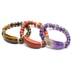 Three crystal bracelets with heart charms and crescent centerpieces in tiger eye, red stone, and amethyst