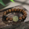 Close up of a wooden bracelet with a carved light green bodhi seed pixiu bead
