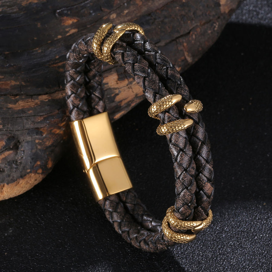 Close up of a dark brown braided leather bracelet with gold tone dragon charms