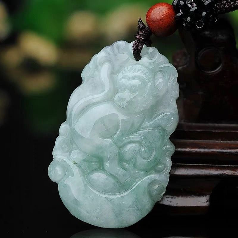 Pale green carved jade pendant featuring a Chinese zodiac animal design on a dark cord