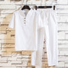 White linen blend men's t-shirt and pants set hanging against a brick wall