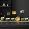 A collection of colorful ceramic teacups with gold interiors arranged on black blocks.