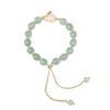 Close up of a green bead bracelet with a white rabbit charm and gold accents