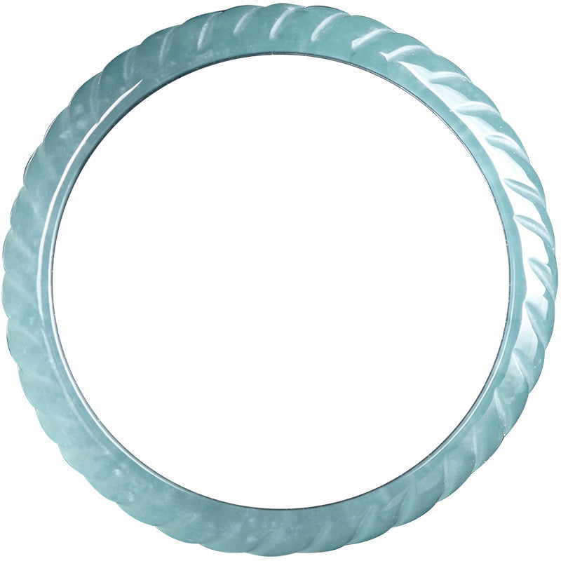 Close-up of a light blue carved jade ring with a dragon scale texture against a black background