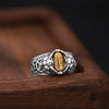 Close up of an antiqued copper ring with a gold tone spinning Pixiu charm on a wooden surface