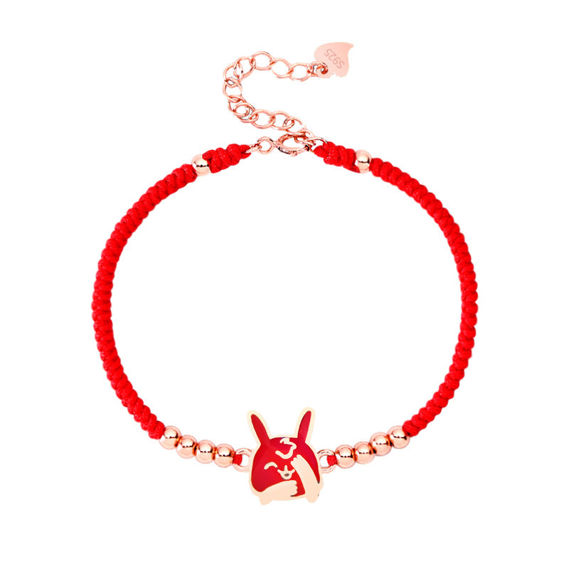 Close up of a red string bracelet with a silver rabbit charm on a wrist