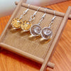 Pair of round glass drop earrings containing yellow dried flowers on a wooden stand