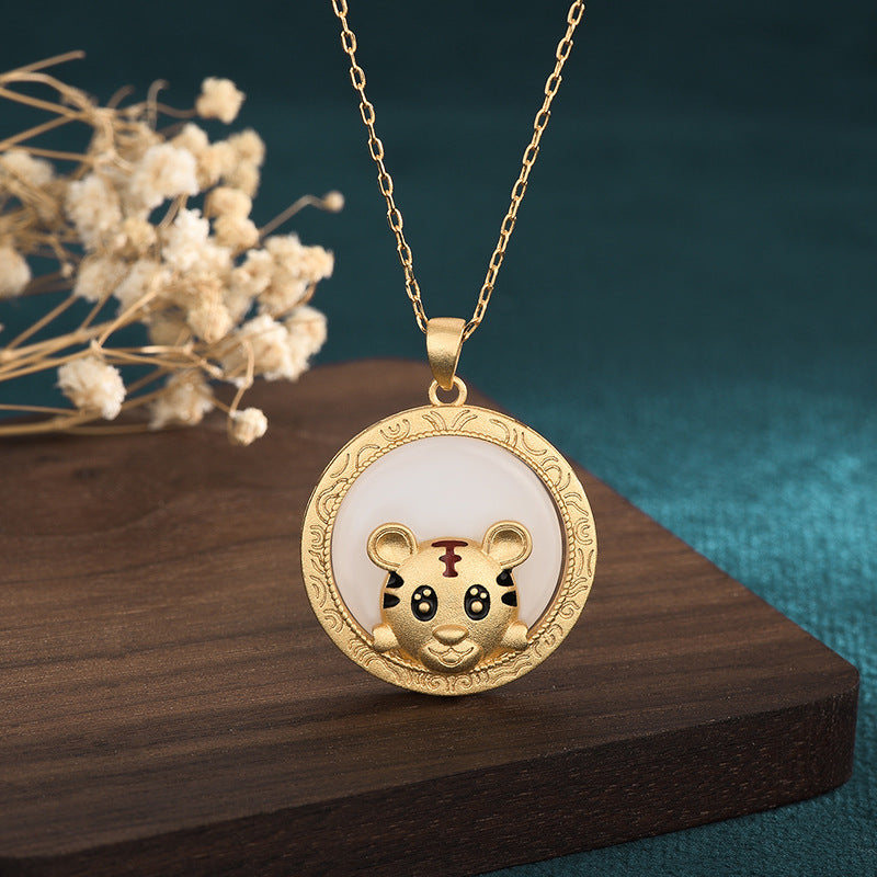 Gold-tone necklace with a round pendant featuring a small tiger charm on a white background