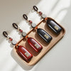 Three wooden keychains with auspicious coins displayed on a light wooden tray