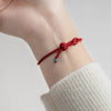 Close-up of a red string bracelet with a knot and jade bead on a wrist