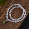 White agate beaded bracelet with a green jade drop charm on a wooden surface