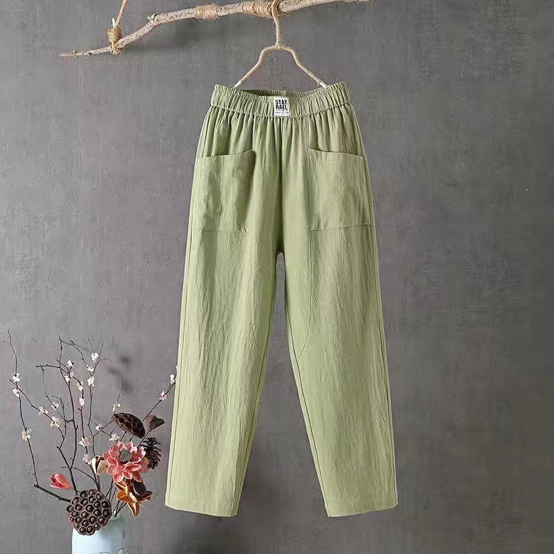 Green cotton linen straight leg pants hanging on a wooden hanger