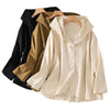 Three hooded jackets in black, khaki, and white hanging on wooden hangers