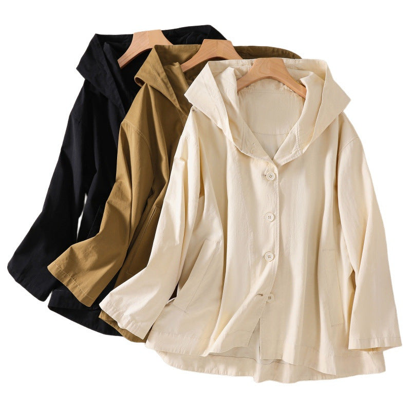 Three hooded jackets in black, khaki, and white hanging on wooden hangers