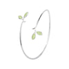 Close up of silver open cuff bracelet with green leaf details on wrist